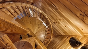 Een wenteltrap in een houten interieur met een plafondventilator.