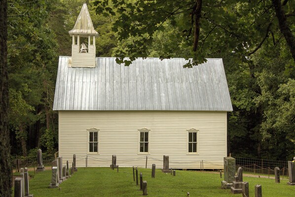 A small, single-story building with a bell tower, surrounded by a cemetery.