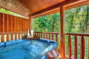 Un jacuzzi en una terraza de madera con vista a un bosque.