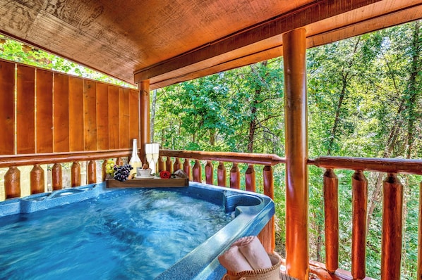 A hot tub on a wooden deck with a view of a forest.