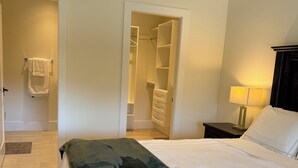 A hotel room with a bed, a nightstand, a lamp, a closet, and a bathroom. - Luxury Suite situated on top of mountain in a prestigious location. (Abbotsford)