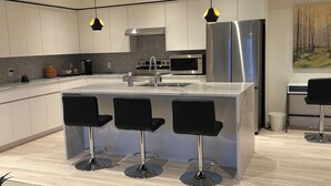 A modern kitchen with a central island, bar stools, stainless steel appliances, and pendant lighting. - Luxury Suite situated on top of mountain in a prestigious location. (Abbotsford)