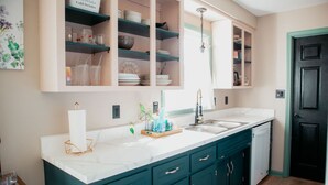 A kitchen with a white countertop, teal cabinets, and a black door.