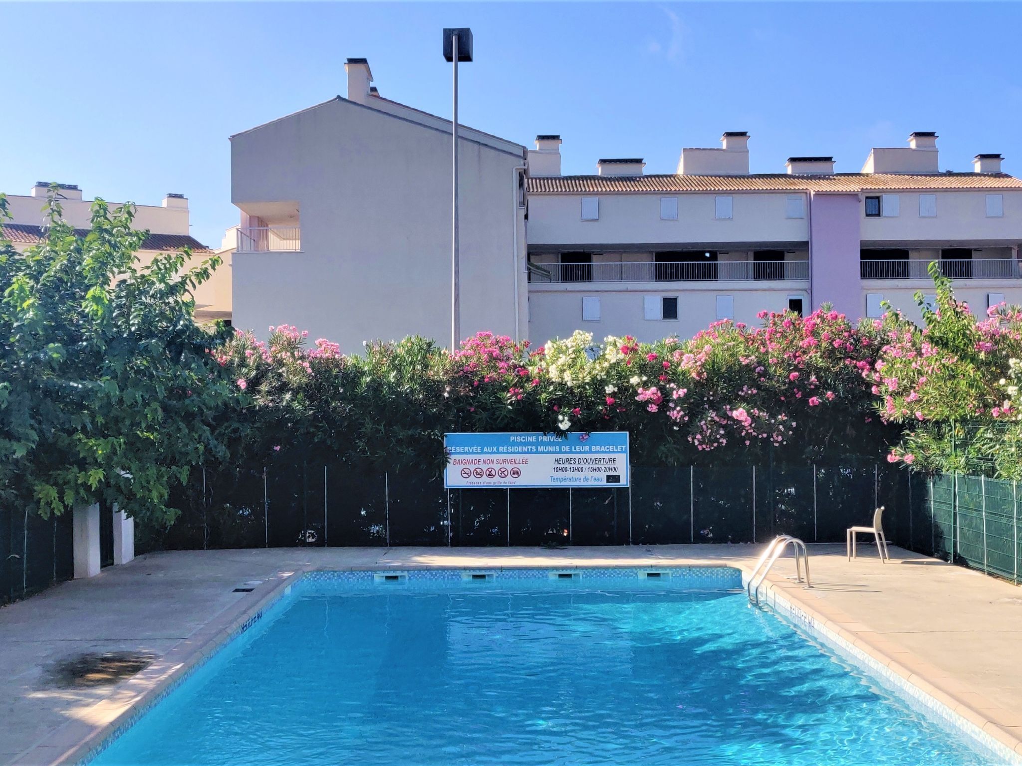 Une piscine avec un panneau indiquant qu’elle est privée et qu’elle a des heures d’ouverture spécifiques.