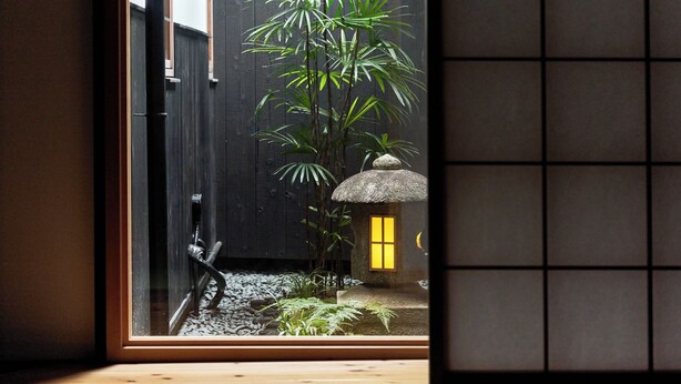 A traditional Japanese garden with a bamboo plant, a stone lantern, and a small thatched structure. - YADORU KYOTO HANARE Shirotaki No Yado (Kyoto)