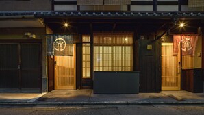 A traditional Japanese building with sliding doors, a wooden bench, and a sign with Japanese characters. - YADORU KYOTO HANARE Shirotaki No Yado (Kyoto)