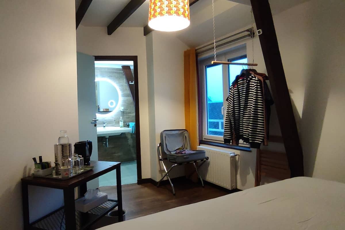 Ein Schlafzimmer mit Bett, Tisch mit Toilettenartikeln, Stuhl und Fenster mit Aussicht.