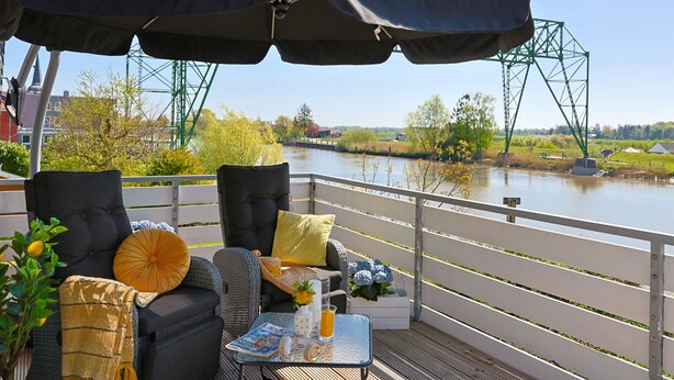 Ein Sitzbereich im Freien mit Tisch, Stühlen und einem großen Sonnenschirm.