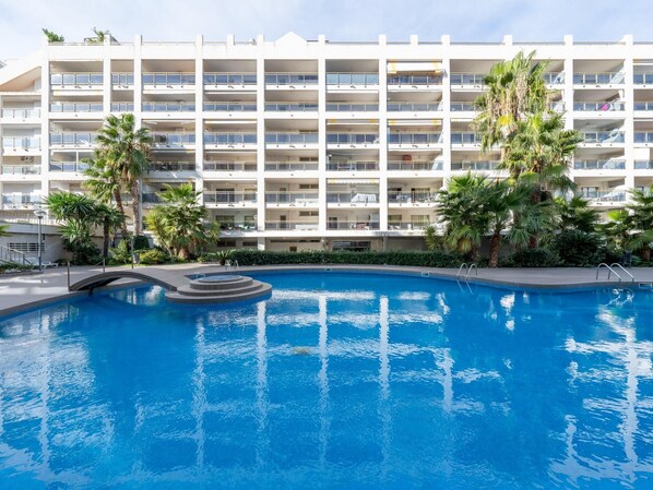 Un hôtel moderne doté d’une grande piscine, de nombreux balcons et d’un aménagement paysager luxuriant.