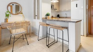 Une cuisine moderne avec un îlot central, des tabourets de bar, un grand miroir rond et une machine à café.