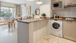 Une cuisine moderne équipée d’un lave-linge et d’un sèche-linge intégrés, un coin repas avec vue et un balcon doté d’un espace salon extérieur.