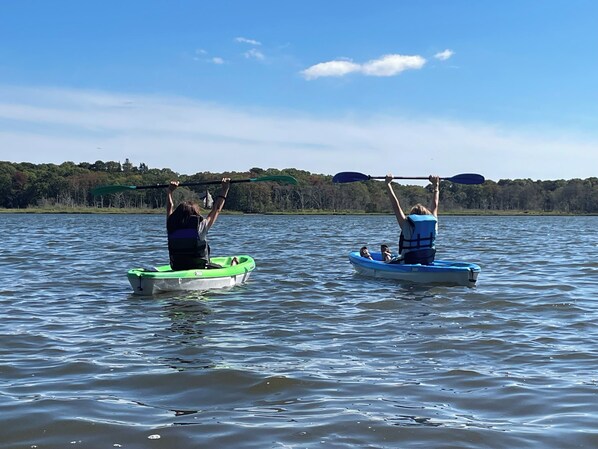 Dos kayaks en un lago tranquilo con una orilla boscosa al fondo.