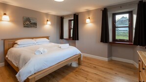 Een slaapkamer met een houten bed, een schilderij aan de muur en een raam met gordijnen.