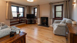 Een gezellige woonkamer met een open haard, een televisie en comfortabele zithoek.