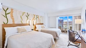 Camera d'albergo con due letti, un balcone vista panoramica e una scrivania con sedia.