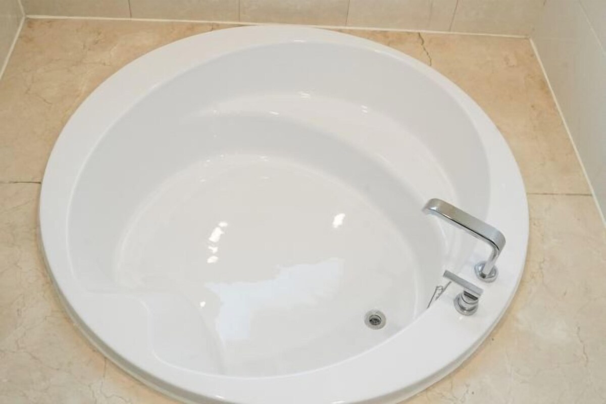 A white bathtub with a single faucet and a drain.