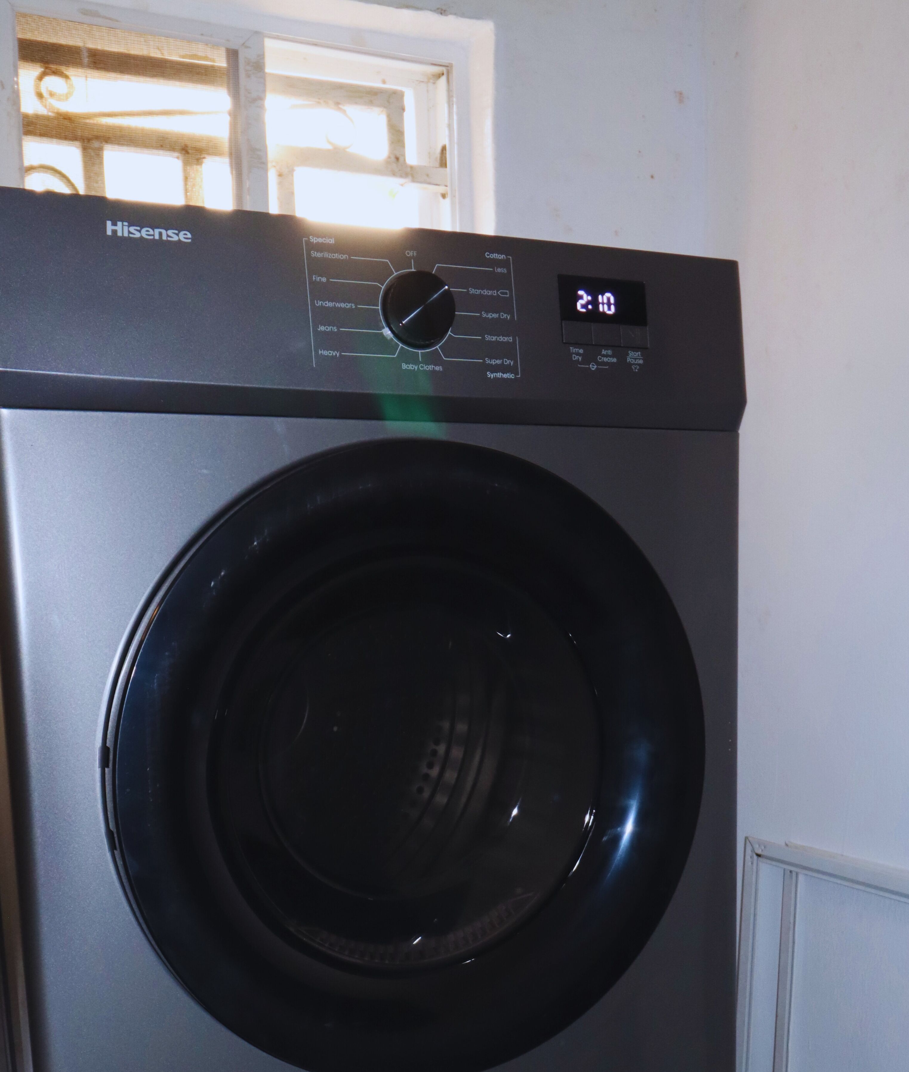 A front-loading Hisense washing machine with a digital display, a control panel with various settings, and a window above it.