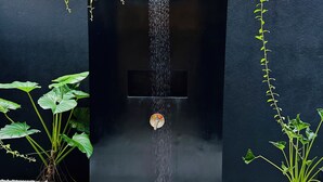 A modern outdoor water feature with a vertical spout, surrounded by white pebbles and potted plants. - Luxury villa in a magnificent natural setting, close to the beach, infinity pool, Ayurveda spa, chef,  (Ahungalla)