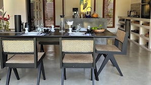 A modern dining area with a high ceiling and exposed beams, featuring a central island with kitchen appliances and a seating arrangement with rattan chairs. - Luxury villa in a magnificent natural setting, close to the beach, infinity pool, Ayurveda spa, chef,  (Ahungalla)