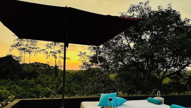 A bed with a white mattress, two blue pillows, a woven tray with a glass and a bottle, and a large umbrella providing shade. - Luxury villa in a magnificent natural setting, close to the beach, infinity pool, Ayurveda spa, chef,  (Ahungalla)