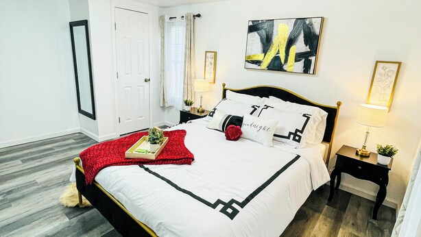 A neatly arranged bedroom with a bed, bedside tables, a mirror, and a ceiling fan. - The Charming Vermont House. (Tulsa)
