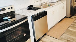 A modern kitchen with white cabinets, stainless steel appliances, a microwave, and a refrigerator. - The Charming Vermont House. (Tulsa)
