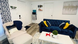 A modern living room with a beige sofa, a blue velvet sofa, and a white coffee table. - The Charming Vermont House. (Tulsa)