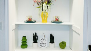 A white shelving unit with decorative items including a vase with flowers, two red teapots, and a sign with a message. - The Charming Vermont House. (Tulsa)