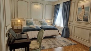 Une chambre avec deux lits, un bureau avec un ordinateur portable, une chaise et un tableau au mur.