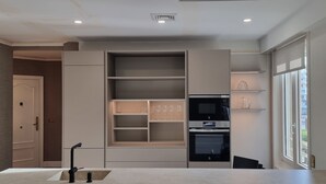 Une cuisine moderne dotée d’appareils électroménagers intégrés, d’une grande fenêtre et d’un design minimaliste.