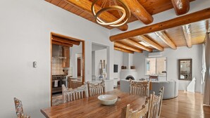 Un vaste espace dédié à la salle à manger, avec une table et des chaises en bois, un grand miroir et une cheminée en arrière-plan.