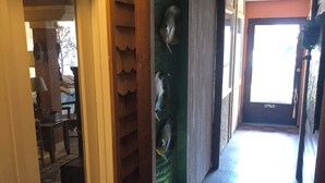 Un pasillo con piso a cuadros, una puerta con picaporte de metal y una pared con sección texturizada verde.