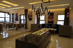 A modern hotel lobby with a marble reception desk, seating areas, and large windows offering city views. - qimampark AlNamas6 (Al Namas)