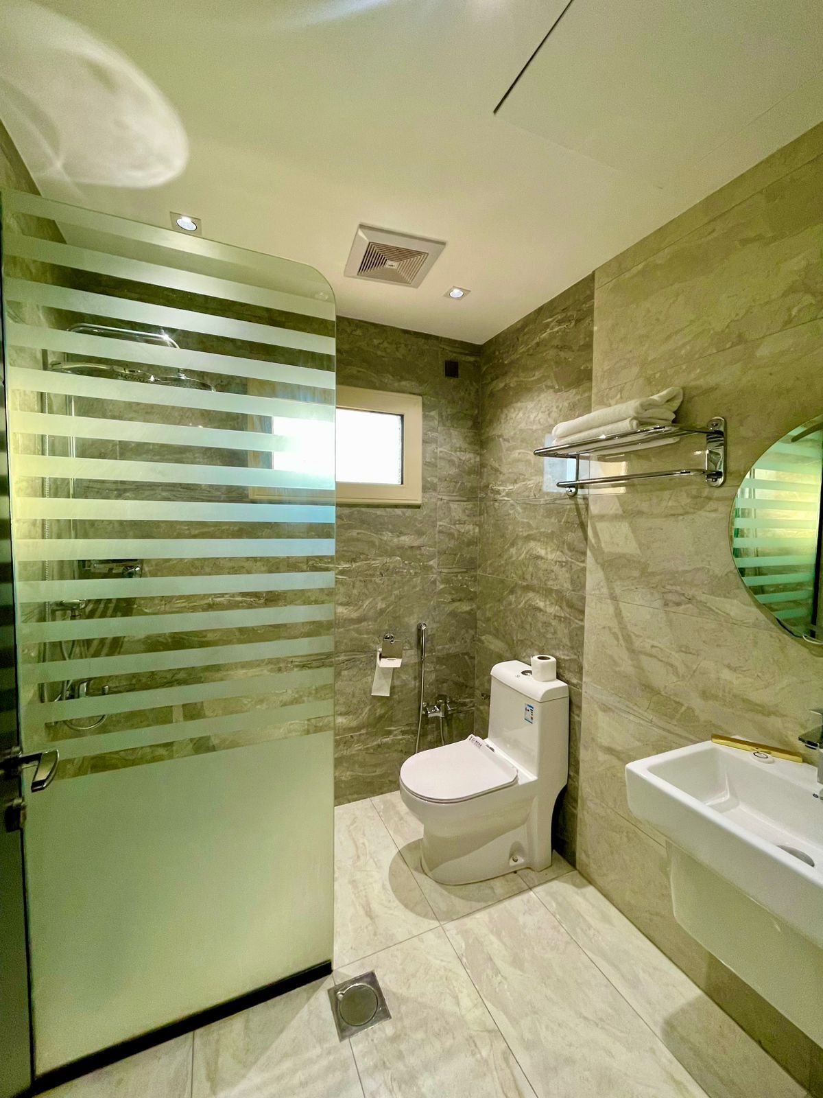 A modern bathroom with a glass shower enclosure, a toilet, and a sink.