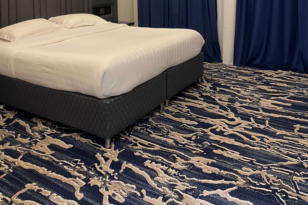 Ein Hotelzimmer mit einem großen Bett, dunklen Vorhängen und einem gemusterten Teppich.