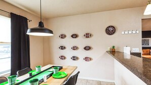 Un comedor con una mesa larga, platos verdes y sillas negras.