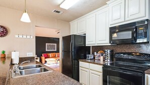 Una cocina moderna con encimeras de granito, electrodomésticos de acero inoxidable y armarios blancos.