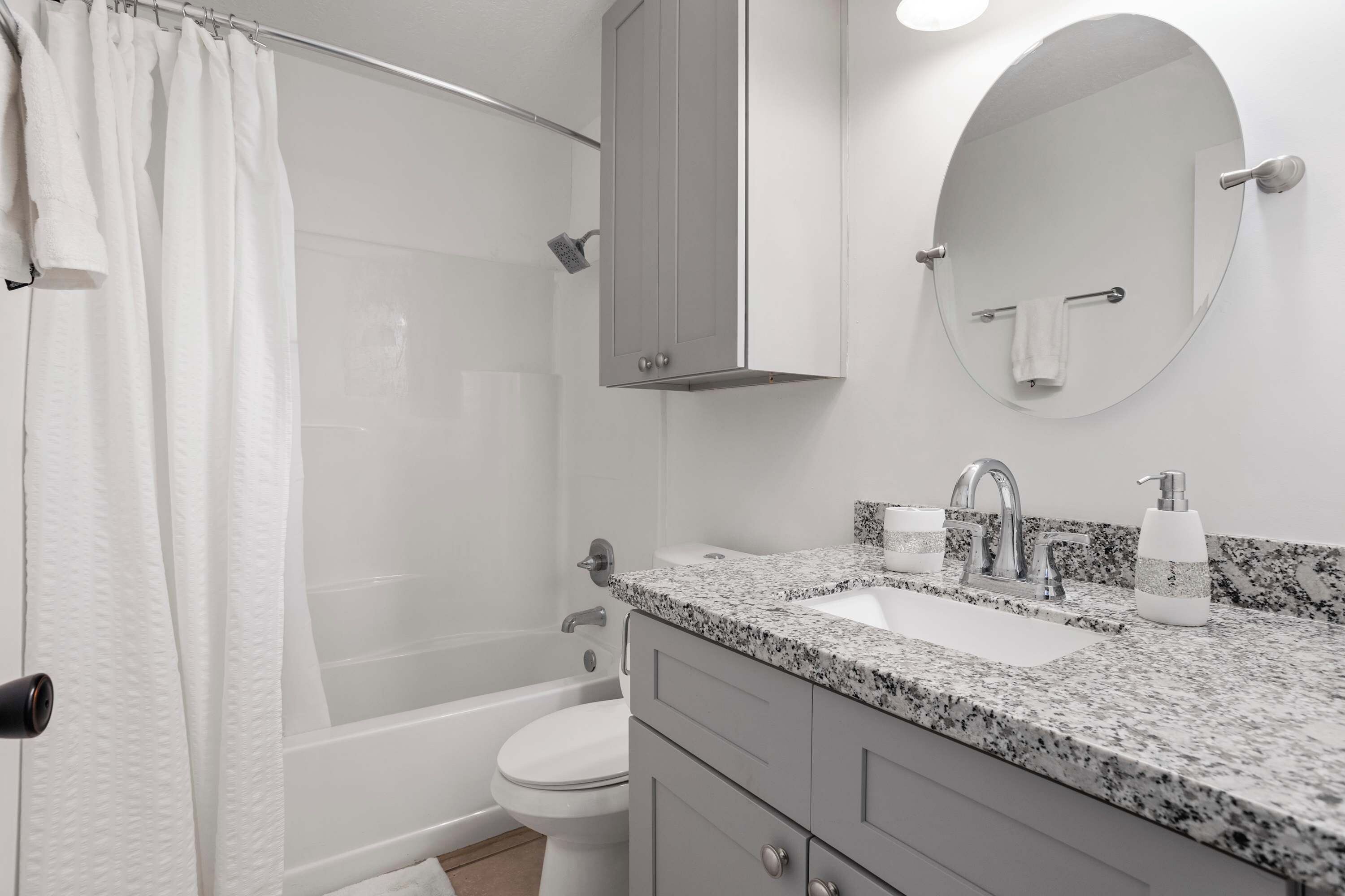 Un baño con ducha, inodoro, lavabo y espejo.