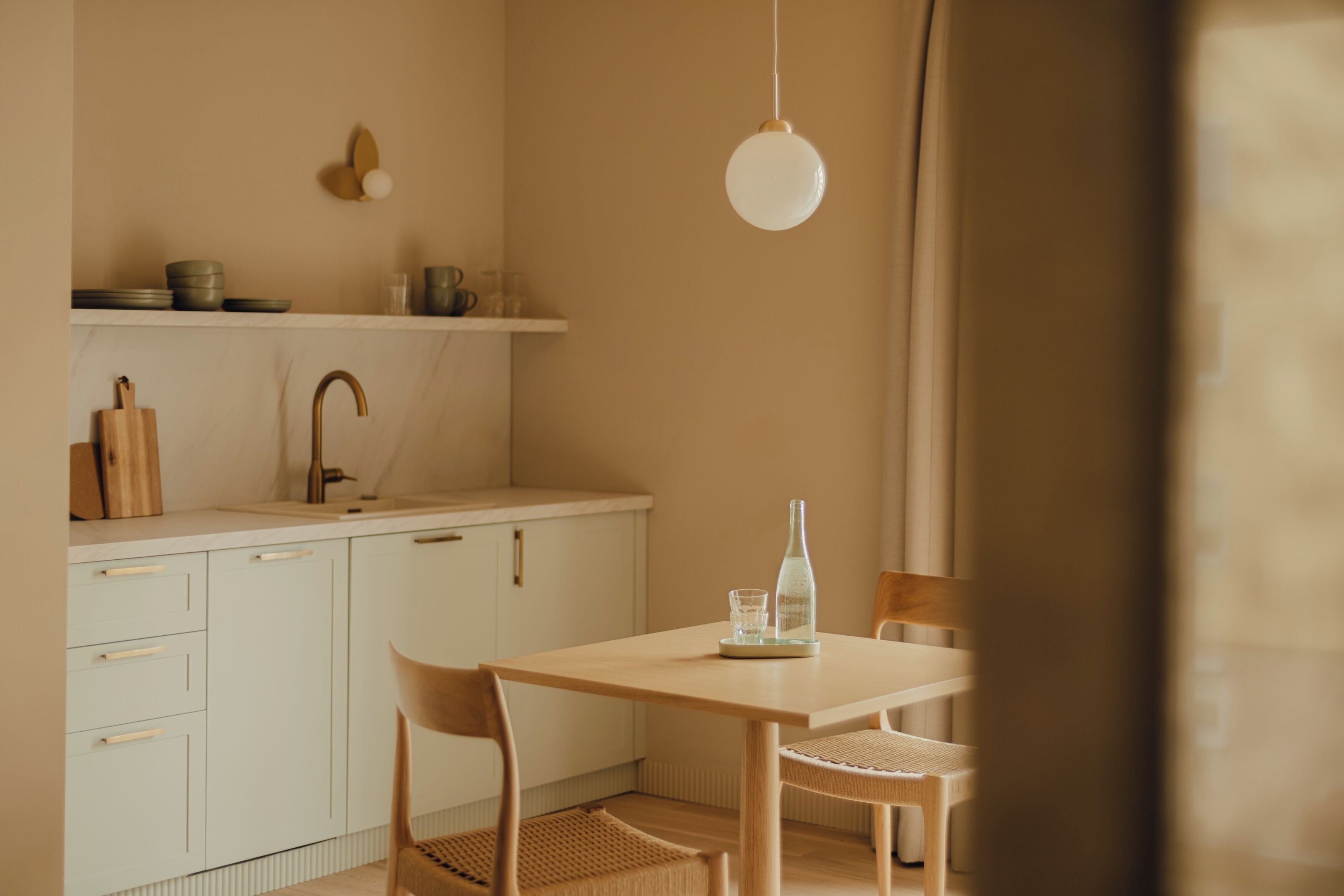 A kitchen with white cabinets, a wooden table, and a hanging light fixture.