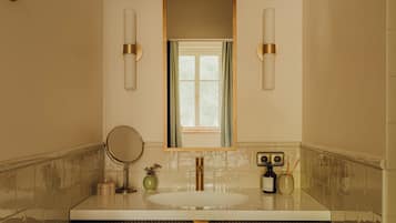 A bathroom with a large mirror, a sink, and two wall-mounted lights.