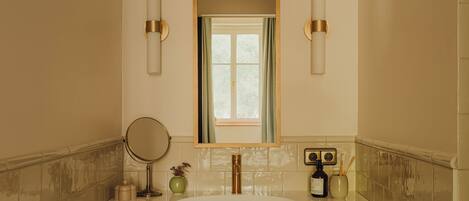 Un baño con un espejo grande, un lavabo y dos luces fijadas a la pared.
