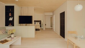 Una sala de estar moderna con una televisión de pantalla plana, un sofá, una mesa de centro con un tablero de ajedrez y una zona de comedor con una mesa y sillas.