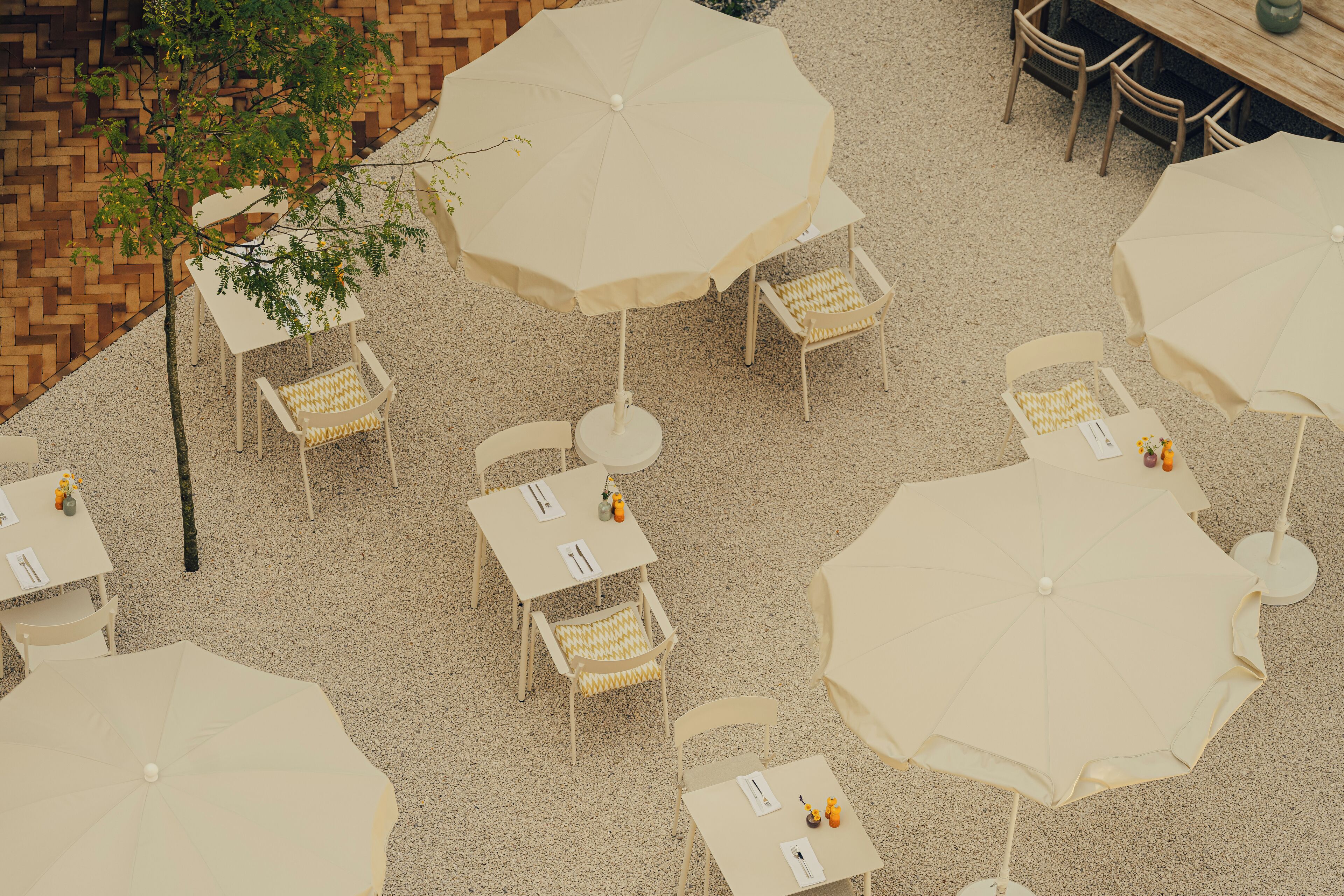 An outdoor seating area with multiple tables and chairs, each with a large umbrella.
