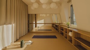 Una habitación amplia con un espejo grande, estantes de madera y una colchoneta para yoga.