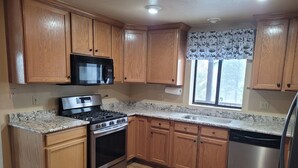A kitchen with wooden cabinets, a stainless steel stove, a microwave, and a dishwasher. - The Treehouse a 4-bedroom log cabin on 3 acres in Heber-Overgaard (Heber-Overgaard)