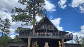 A two-story cabin with a stone fireplace, a balcony, and a large tree in front. - The Treehouse a 4-bedroom log cabin on 3 acres in Heber-Overgaard (Heber-Overgaard)