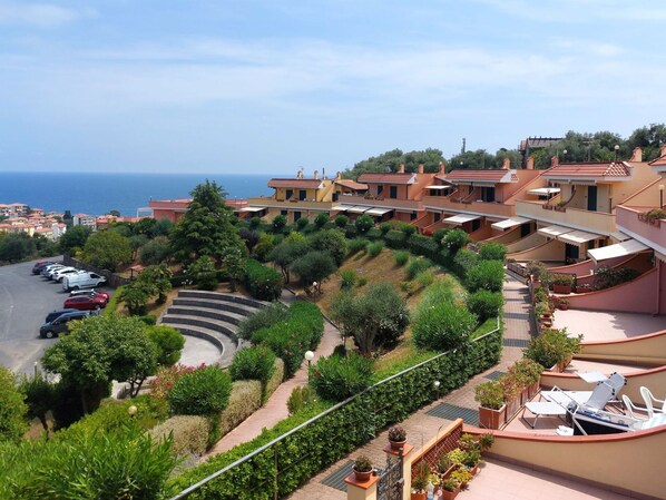 A coastal residential area with terraced houses, a curved driveway, and a view of the sea.