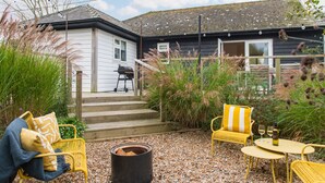 Une maison dotée d’une terrasse en bois, d’un espace salon extérieur et d’un coin barbecue.