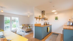 Une cuisine compacte dotée d’un îlot central, un coin repas avec une table jaune et un espace de vie comprenant un canapé et une table basse.