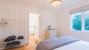 Une chambre avec un grand lit, une table de chevet, une armoire et une fenêtre donnant sur un paysage verdoyant.